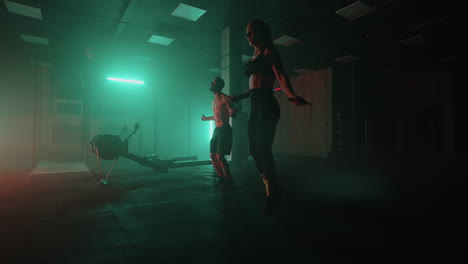 A-man-and-a-woman-in-a-colored-neon-red-and-blue-light-in-slow-motion-jump-rope-together.-Endurance-training.-The-concept-of-athletic-and-strong-couples